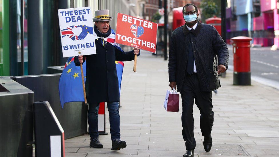 Kwasi Kwarteng walks by Brexit protestor in London